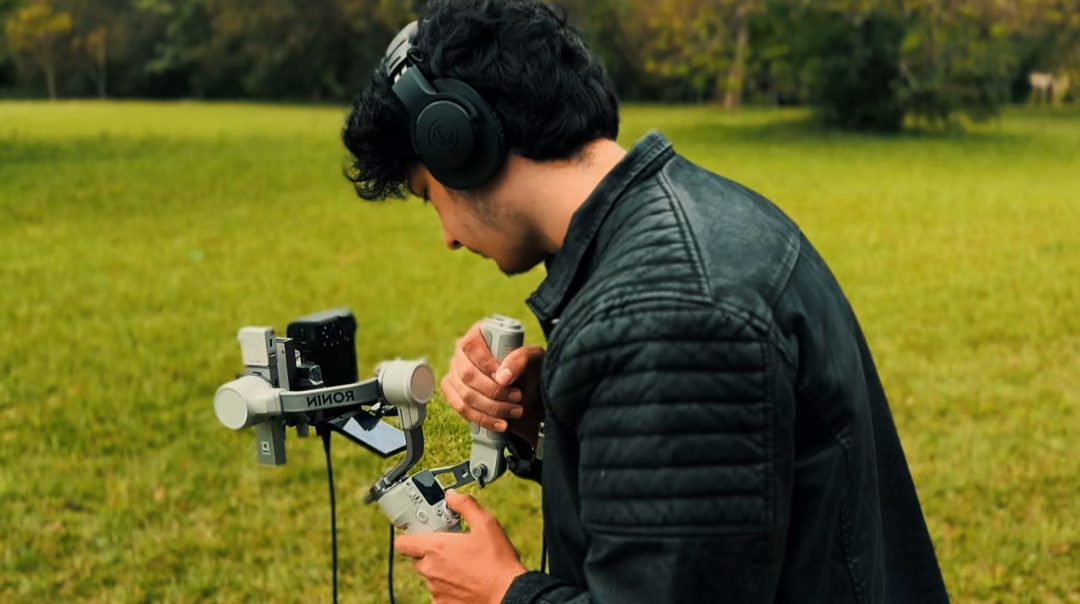 Camarógrafo con auriculares preparando la cámara en un estabilizador